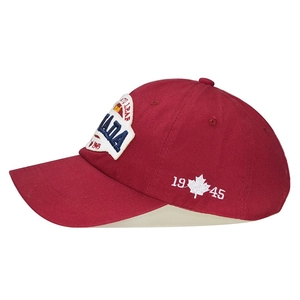 Close-up of the CANADA embroidery and maple leaf design on the side of a red cotton cap