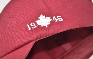 Detail of red cotton baseball cap with white maple leaf and 1945 embroidery on the back