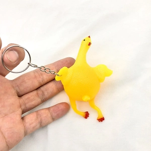 Macro shot of creative yellow laying chicken keychain with red comb on white background