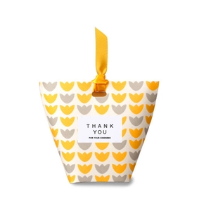 Detail of yellow gift box with tulip pattern and Thank You text on white background