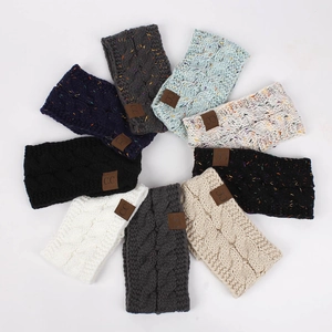 Flat lay of colorful knitted winter headbands featuring textured cable knit and CC leather patch