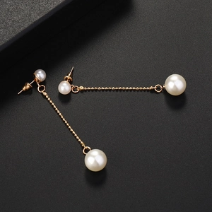 Elegant gold chain tassel earrings with white pearls on a textured black background