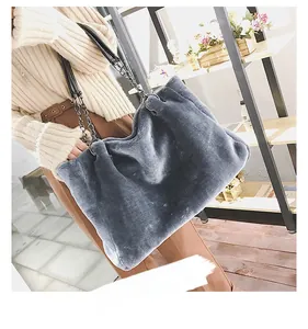 Detail of grey plush tote bag with black metal chain strap on a model shoulder
