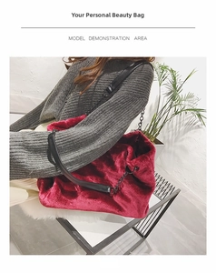 Detail of red plush tote bag featuring black leather wide strap and decorative chain link