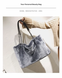 Detail view of a large grey faux fur tote bag featuring elegant black leather and chain straps