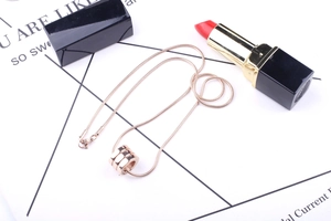 Detailed view of a rose gold spiral pendant on a sleek snake chain with a lipstick accent