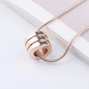Macro shot of a rose gold cylindrical pendant featuring three grooves on a snake chain
