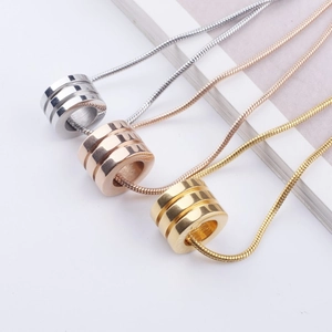 Macro shot of gold, rose gold, and silver triple-ring pendants on snake chains