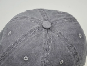Macro shot of grey washed cotton baseball cap top with stitching and eyelets detail