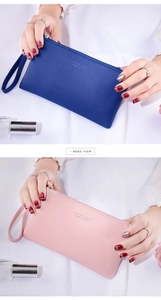 Detail of slim faux leather wallets with wrist straps in navy blue and soft pink colors