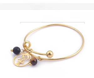 Détail du bracelet plaqué or 18K avec breloque fille, pierre de lave et oeil de tigre