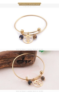 Détail d'un bracelet doré réglable avec breloque fille, pierre de lave et perle œil de tigre