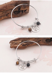 Détail d'un bracelet ajustable en acier inoxydable avec perle œil de tigre et charme