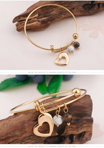 Détail d'un bracelet doré avec pendentif cœur et perles en marbre et œil de tigre