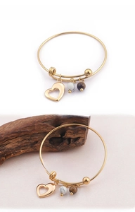 Détail du bracelet doré avec breloque cœur, perle marbrée et pendentifs œil de tigre