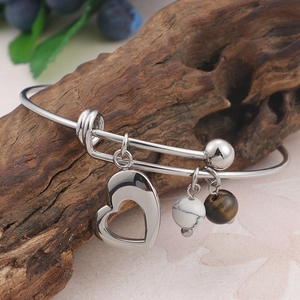 Bracelet jonc en acier inoxydable avec breloque cœur et perles marbrées sur bois