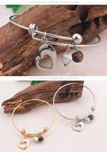 Détail de bracelets cœur dorés et argentés avec perles de marbre et d'œil de tigre sur fleurs
