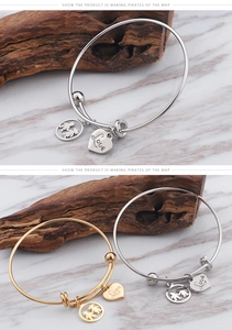 Detail of gold and silver steel bangles with Love heart and boy-girl charms