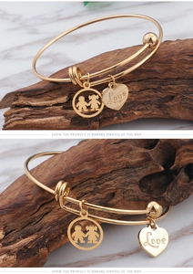 Detail of adjustable gold titanium bracelet with boy-girl charm and Love heart pendant