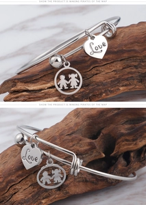 Detail of silver titanium steel bracelet featuring a Love heart and children pendants