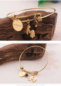Detailed close-up of gold titanium steel bangle with heart mom charms and tiger eye stone