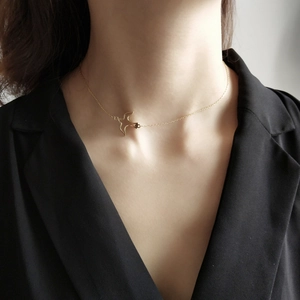 Detailed close-up of a golden bird pendant necklace worn by a model in a black blazer