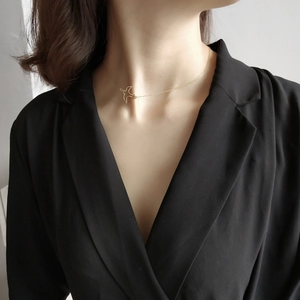 Close-up of a minimalist gold flying bird pendant necklace on a model's neck