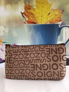Detailed view of a brown jacquard makeup bag with letter patterns and zipper closure