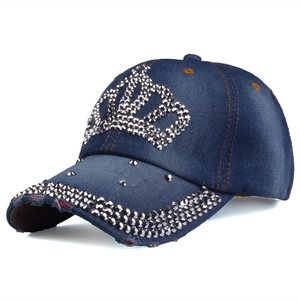 Détail du motif couronne en strass et denim vieilli sur une casquette de baseball bleue