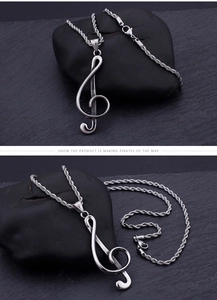 Macro shot of silver treble clef music pendant with a rope chain on stone background