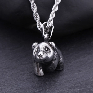 Vintage metal panda pendant necklace with twisted chain on stone background