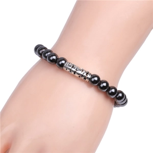 Dettaglio di bracciale con perle magnetiche nere e tubo d'argento traforato al polso