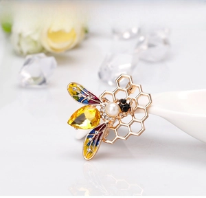 Macro detail of bee brooch with colorful enamel wings and yellow pear-cut gemstone
