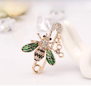 Detail of bee brooch with green enamel wings and crystal honeycomb pendant on ceramic
