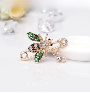 Detail of bee brooch with green enamel wings and rhinestones on a safety pin design