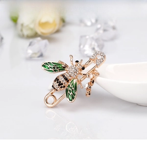 Macro detail of bee brooch featuring green enamel wings and sparkling crystal inlay