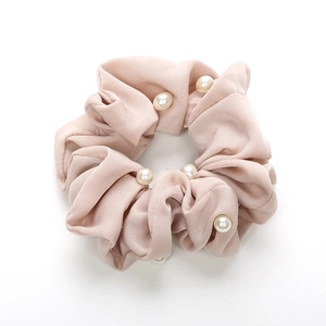 Détail de la texture satinée lisse et des perles sur le chouchou rose élégant