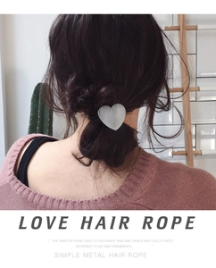 Detail of silver brushed metal heart hair tie worn on a simple ponytail by a model