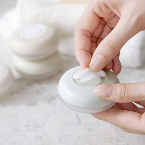 Portable travel lotion bottle set with compact cream jars on a marble surface