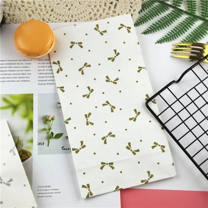 Detailed view of white paper gift bag with golden bow pattern for sweets and bakery