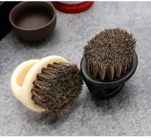 Close-up of beige and black barber beard brushes with dense bristles on a retro countertop