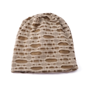 Detailed close-up of tan and beige knit beanie featuring vintage distressed hollow cutouts