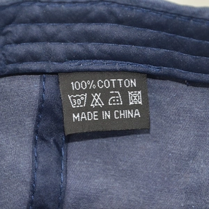 Detail of 100% cotton wash care label and stitching on dark blue denim baseball cap