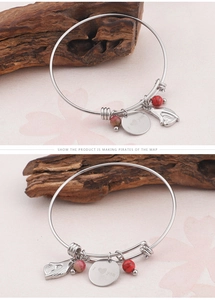 Detail of silver bangle with I Love You charm, red beads, and angel wing pendant charm