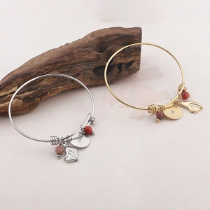 Gold and silver heart bracelets with red beads and I Love You pendants on driftwood