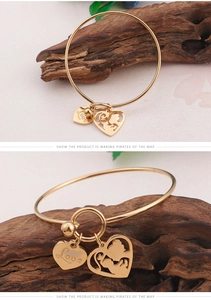 Detail of gold titanium steel heart bangle with Love engraving and silhouette charm