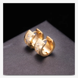 Close-up of 18K gold huggie earrings with matte finish and sparkling cubic zirconia stones