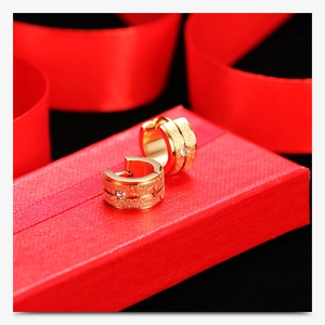 Close-up of 18K gold frosted hoop earrings with small zircon on a red gift box