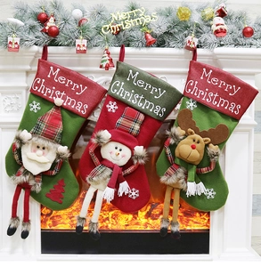 Trois chaussettes de Noël avec Père Noël, bonhomme de neige et renne sur la cheminée
