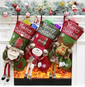 Trois chaussettes de Noël avec Père Noël et Bonhomme de neige suspendues devant la cheminée